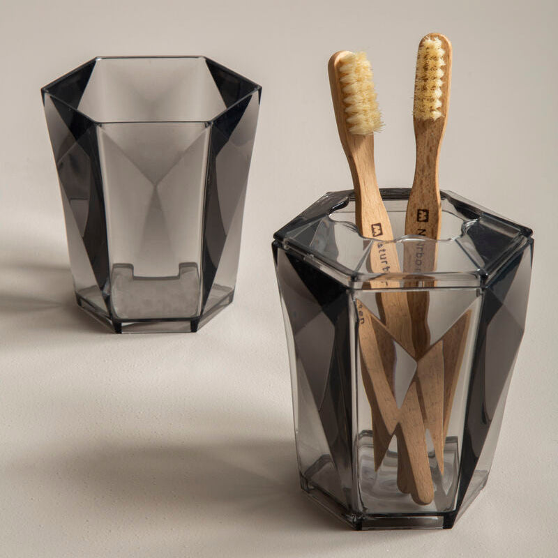 Two geometric glass containers with wooden toothbrushes on a neutral background