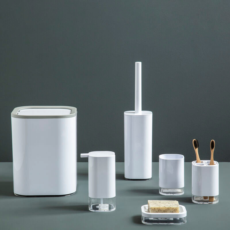 Set of bathroom accessories including a trash can, toilet brush holder, and other small containers on a dark surface with a gray background.