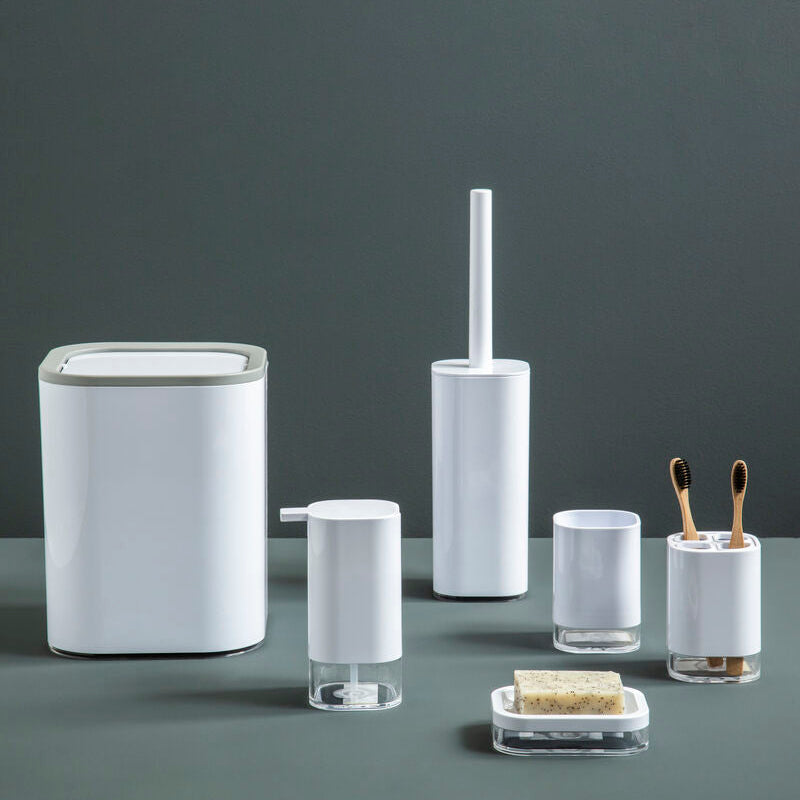 Set of bathroom accessories including a trash can, toilet brush holder, and other small containers on a dark surface with a gray background.