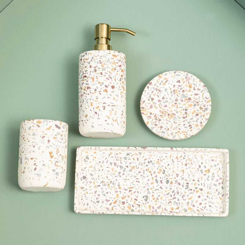 Bathroom accessories set with a dispenser, bottle, and coasters on a green background