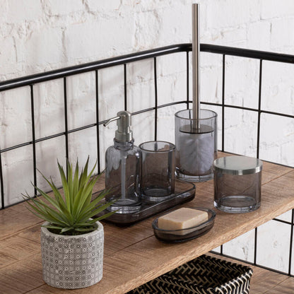 Bathroom shelf with various items including a plant, soap, and glass containers against a white brick wall.