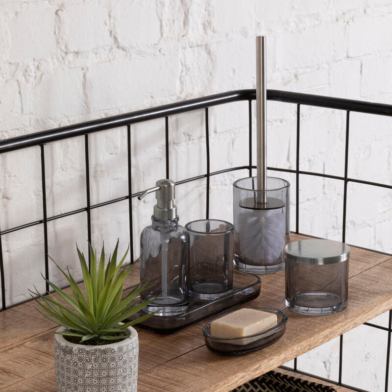 Bathroom shelf with various items including a plant, soap, and glass containers against a white brick wall.