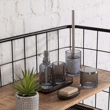 Bathroom shelf with various items including a plant, soap, and glass containers against a white brick wall.