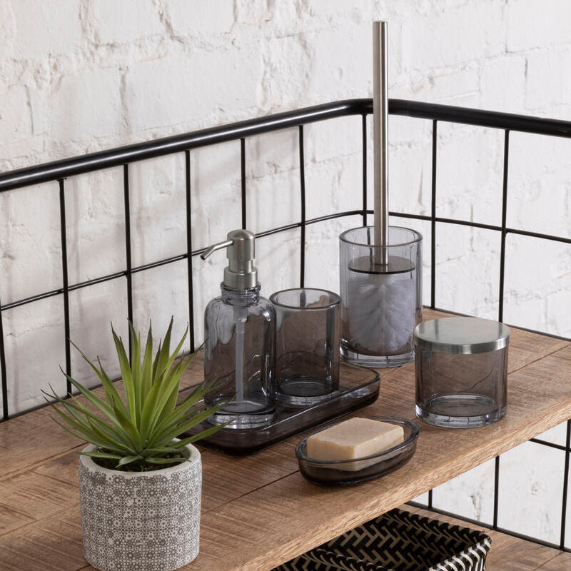 Bathroom shelf with various items including a plant, soap, and glass containers against a white brick wall.