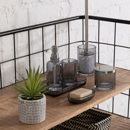 Bathroom shelf with various items including a plant, soap, and glass containers against a white brick wall.