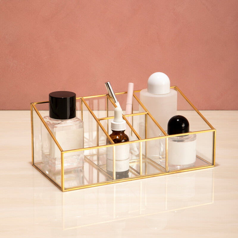 Glass cosmetic organizer with various bottles on a pink background