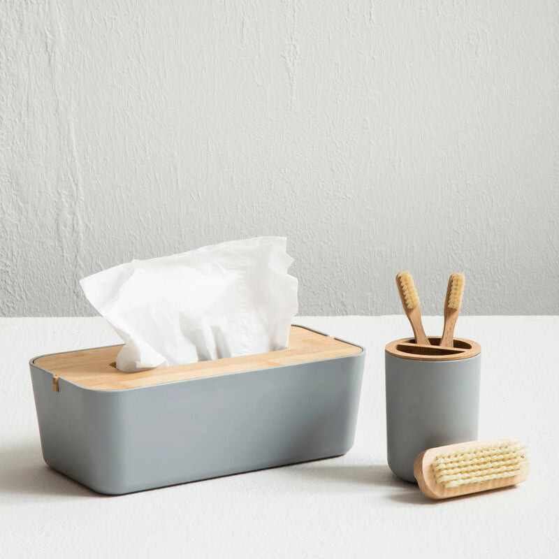 Gray tissue box with wooden lid, small gray container with bamboo items, and a scrubber on a white surface.