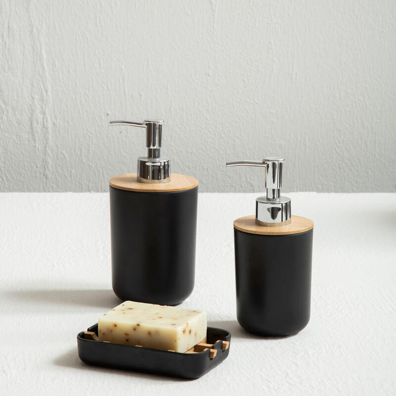 Black soap dispensers with wooden accents on a white surface.