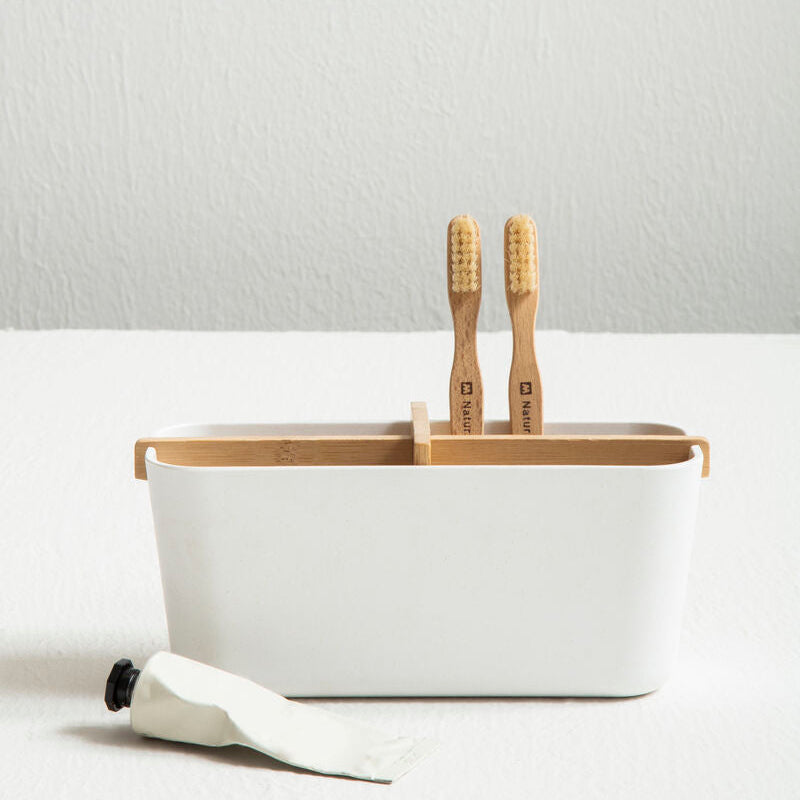 White container with wooden utensils on a light gray background
