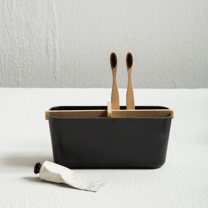 Black container with two wooden toothbrushes on a white surface