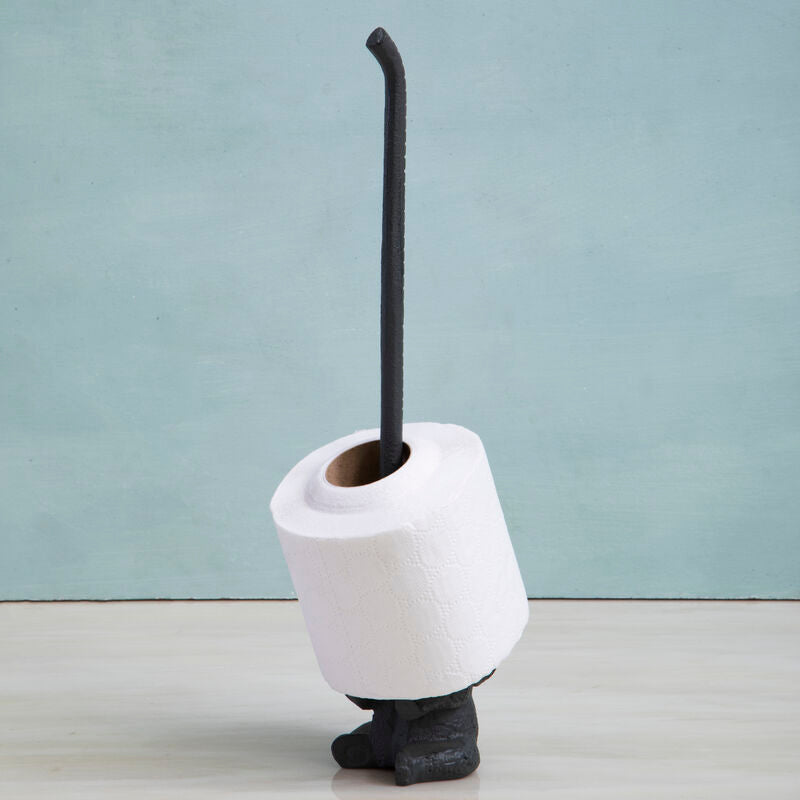 White toilet brush holder with a black brush against a light blue wall.