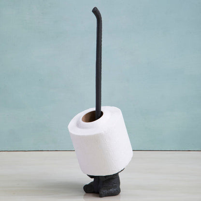 White toilet brush holder with a black brush against a light blue wall.
