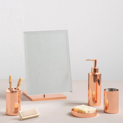 Bathroom accessories including a mirror, soap dispenser, and cups on a light surface.