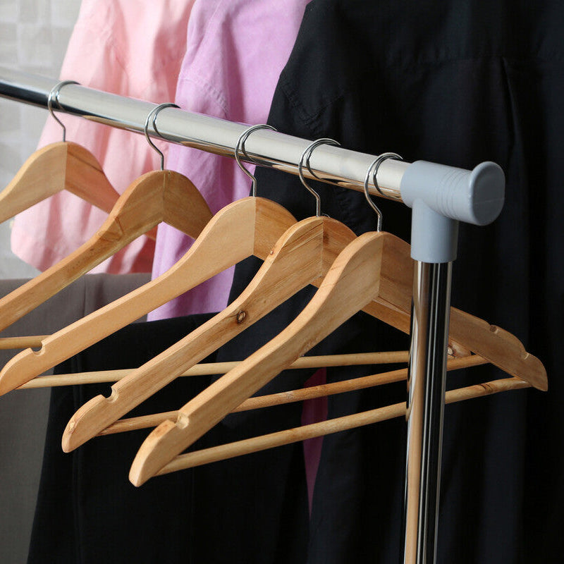 Set of wooden hangers on a metal rod with clothes in the background