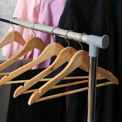 Set of wooden hangers on a metal rod with clothes in the background
