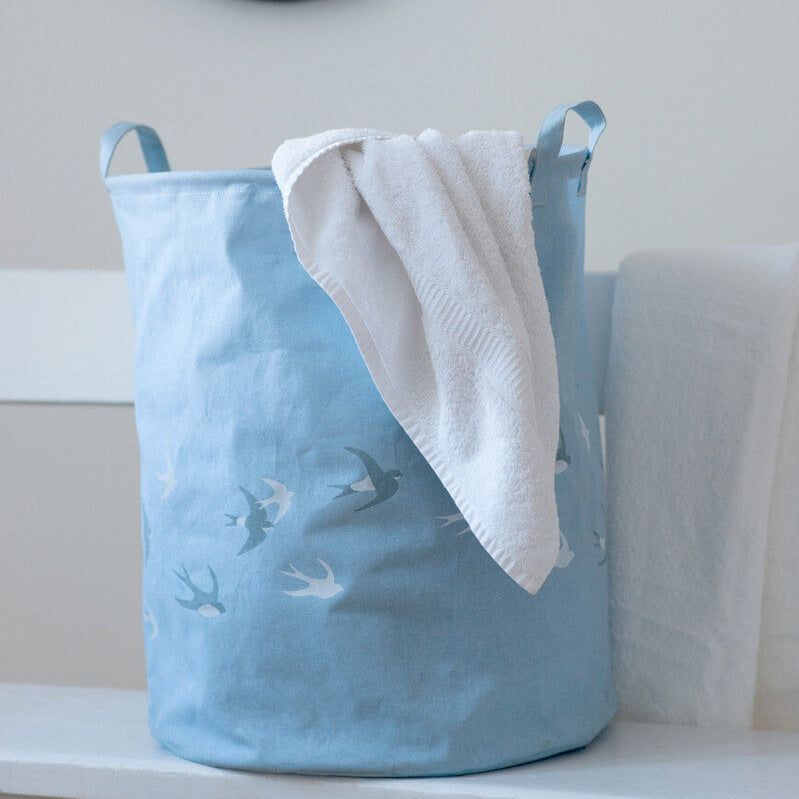 Blue textured laundry basket with a white towel on a white surface, mirror in the background