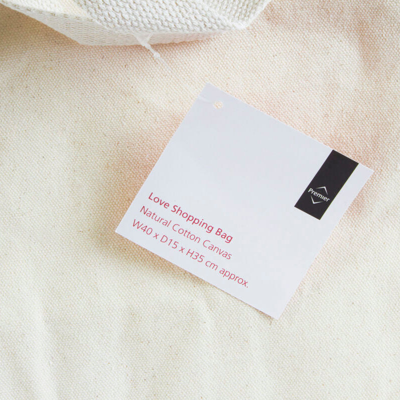 White cotton bag with a label on a beige fabric background