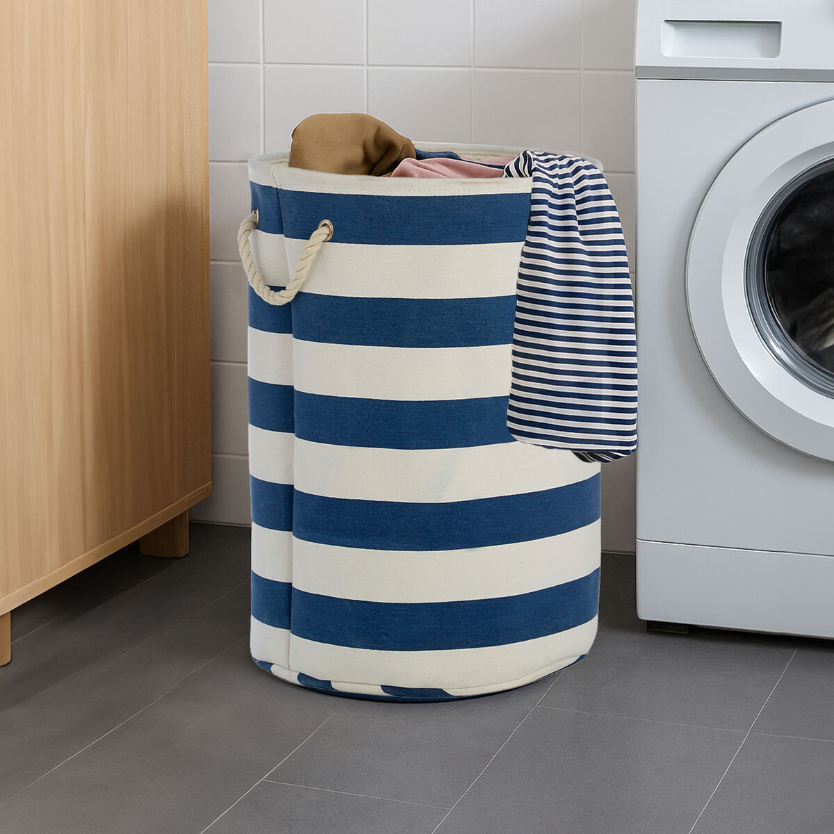 Blue and white striped laundry basket with clothes in front of a washing machine.