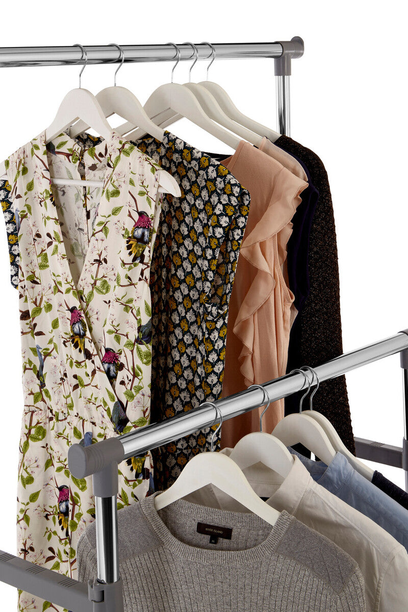 Clothing rack with various garments including a floral dress, patterned top, and sweaters on hangers.