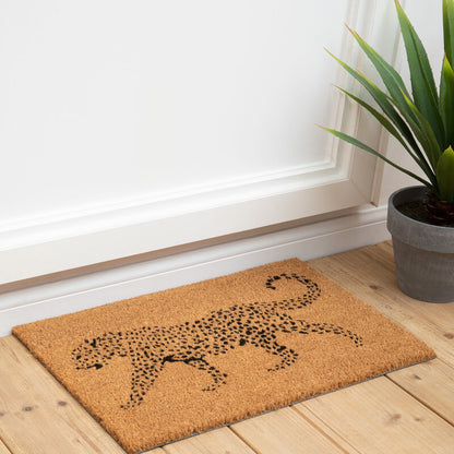 Doormat with a leopard design on a wooden floor next to a plant