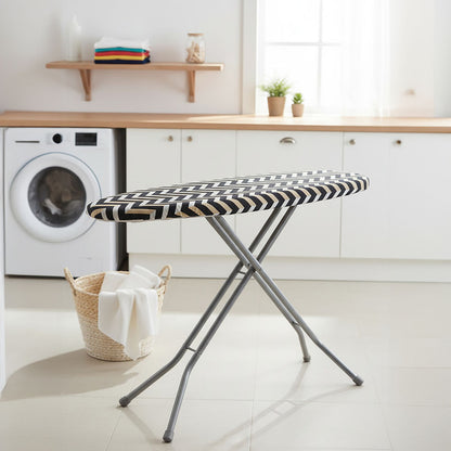 Black and white checkered ironing board in a laundry room with washing machine and shelves.