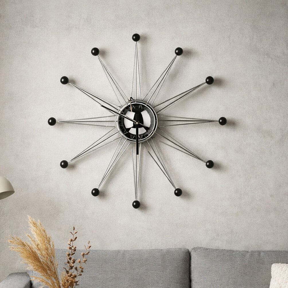 Decorative wall clock on a gray wall above a sofa with a lamp and vase.