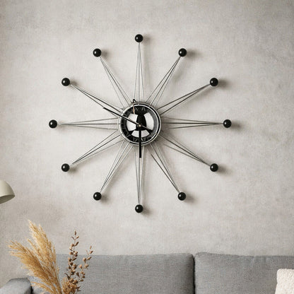 Decorative wall clock on a gray wall above a sofa with a lamp and vase.