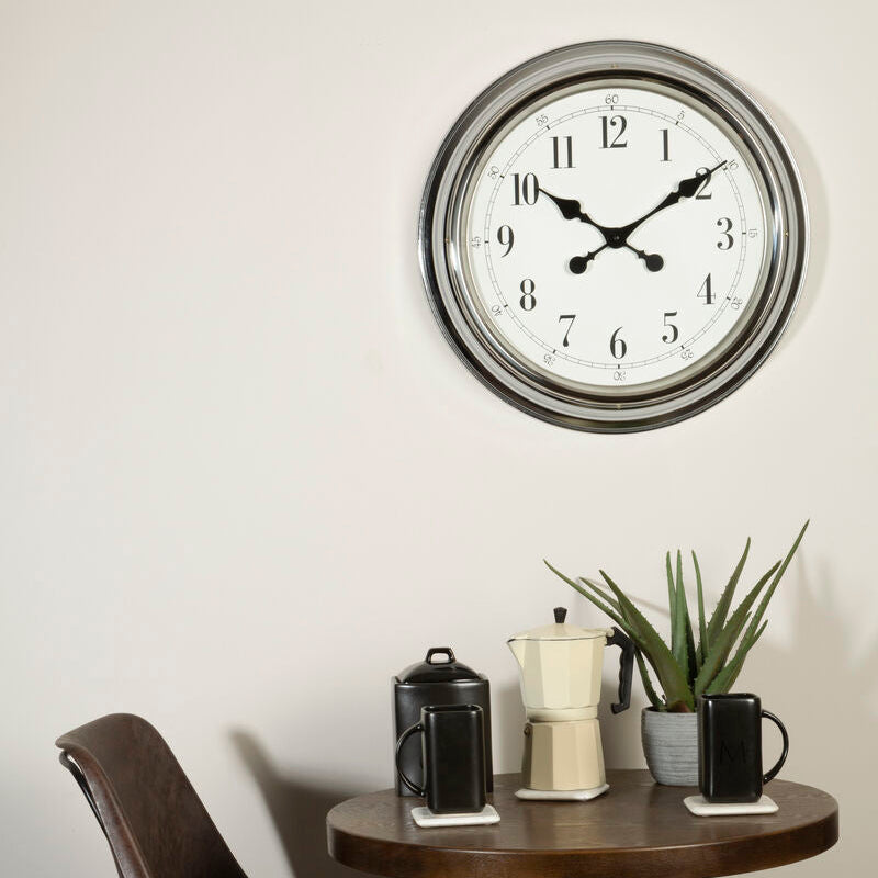 Wall clock on a wall above a small round table with chairs and decor items.