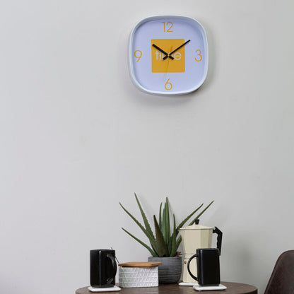 Wall clock on a light gray wall above a small table with decor items.