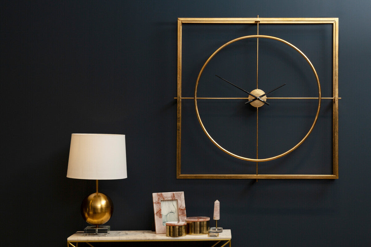 Decorative wall clock with gold frame and modern design on a dark wall.