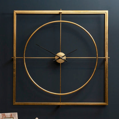 Gold wall clock on a dark wall with a lamp and decorative items on a table.