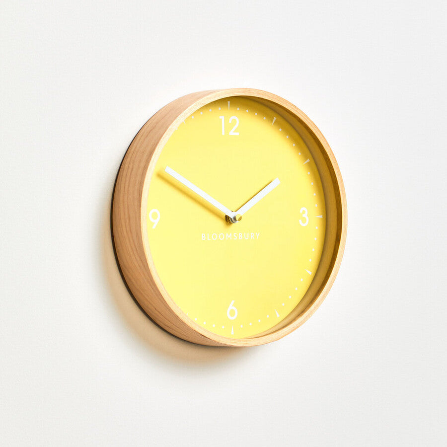 Yellow wall clock with wooden frame on a white background