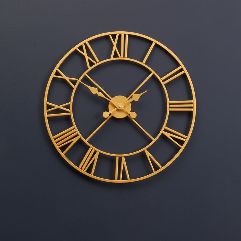 Gold wall clock with Roman numerals on a dark blue wall
