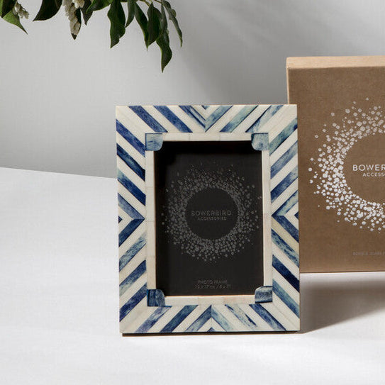 Set of decorative photo frames on a white surface with a plant in the background