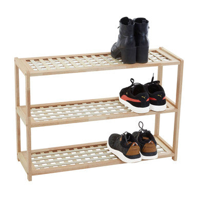 Wooden shoe rack with three shelves holding various shoes on a white background