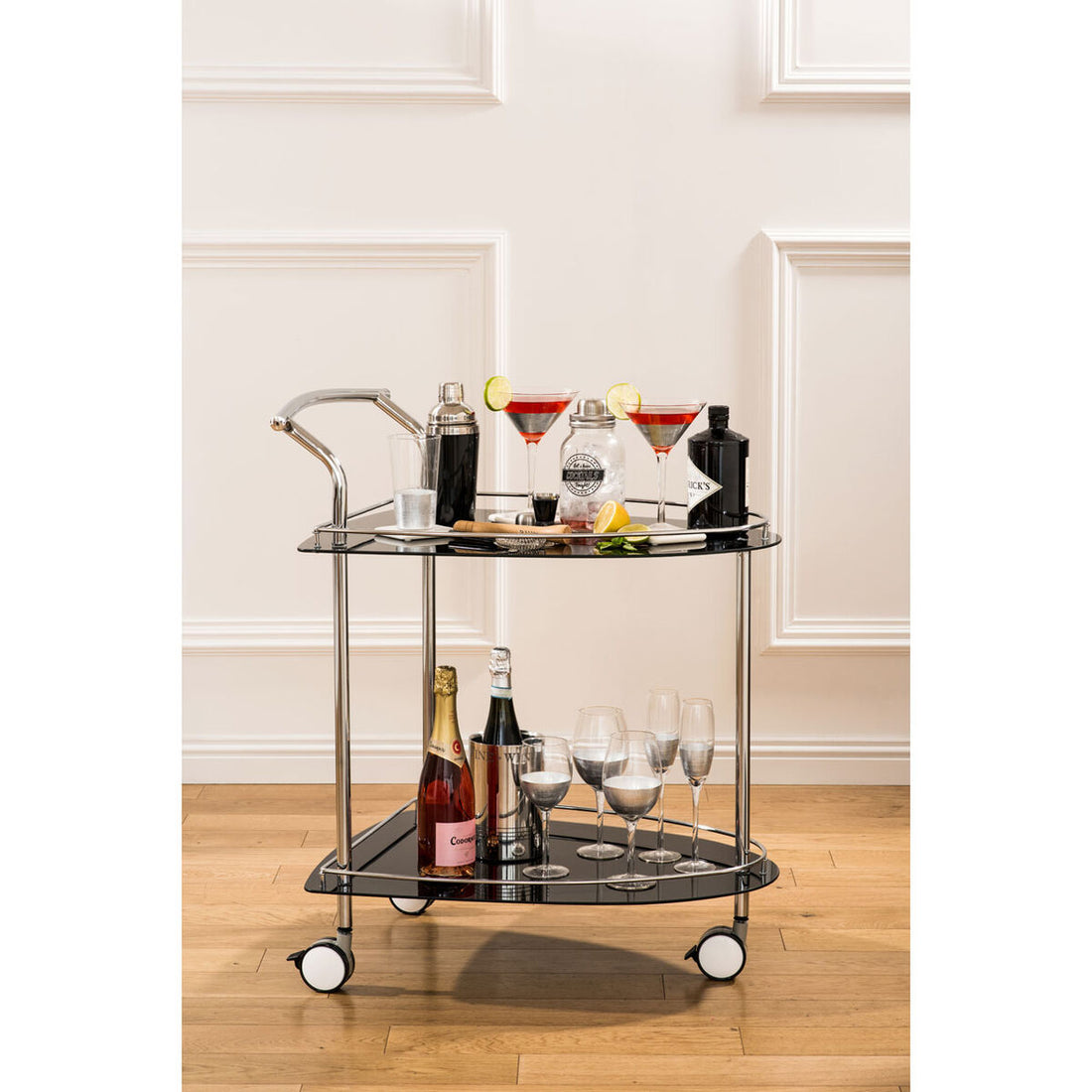Bar cart with drinks and glasses on a wooden floor.
