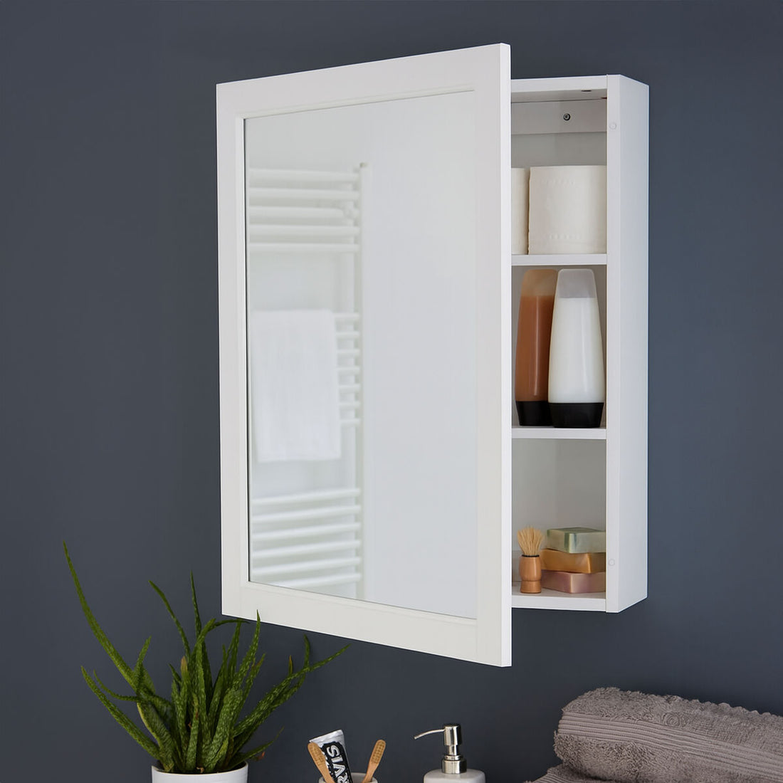 White wall-mounted cabinet with mirror on a dark gray wall, containing bathroom items.
