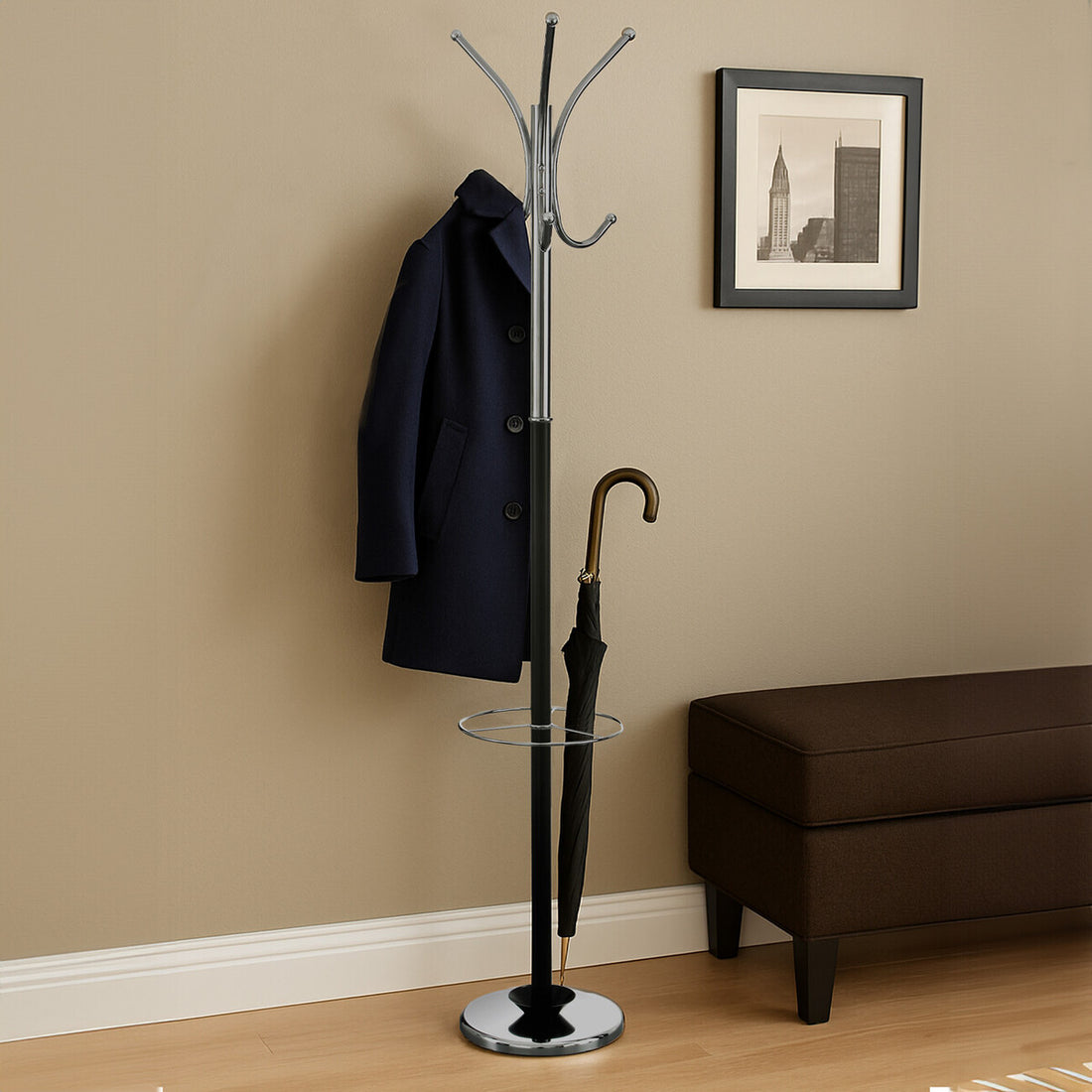 Coat rack with a black coat and umbrella against a beige wall with a framed picture.