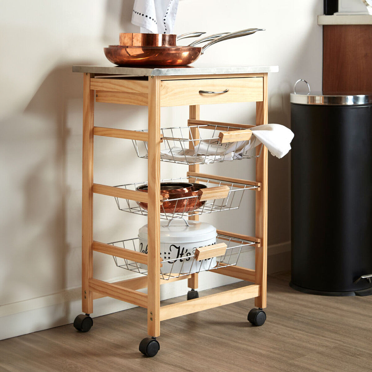 Wooden kitchen cart with metal shelves and pots on a wooden floor.