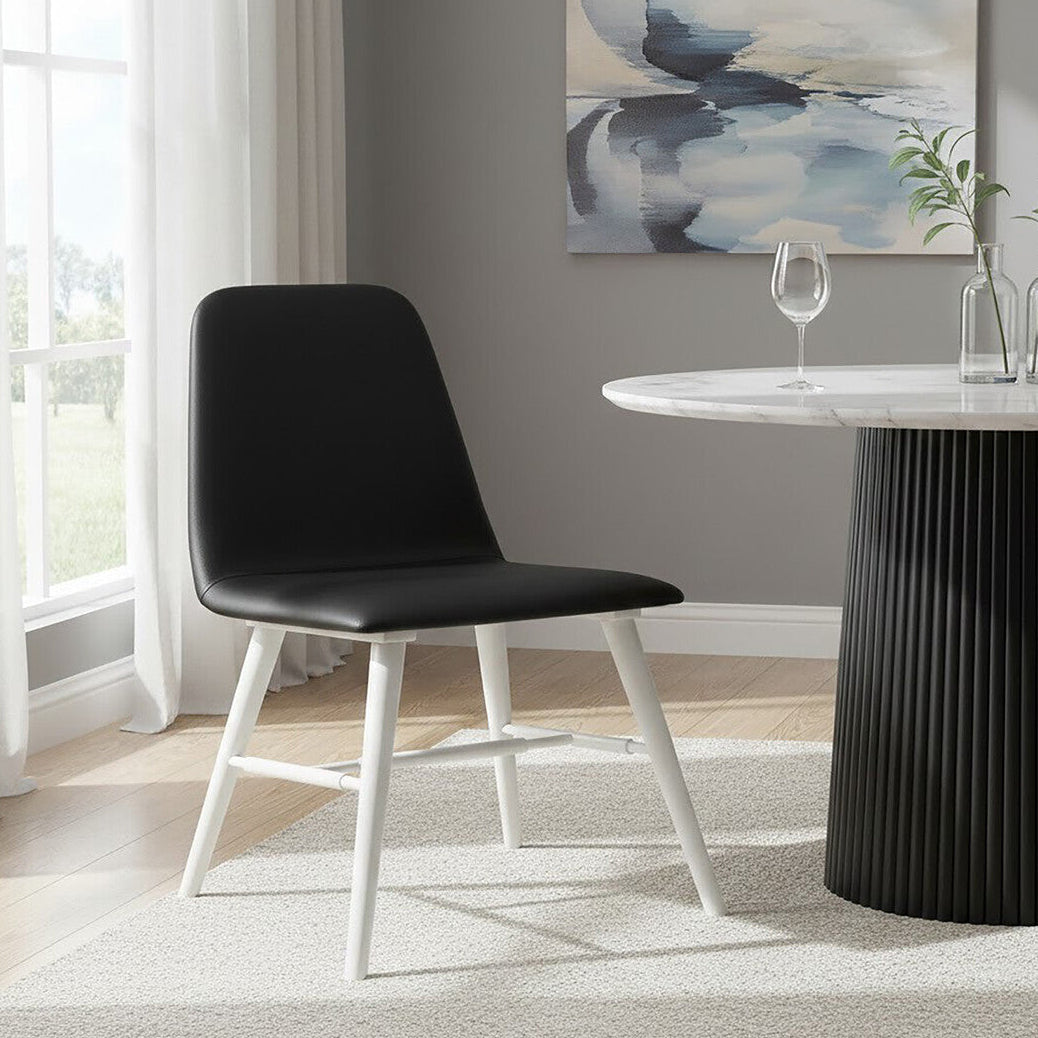 Black chair with white legs in a modern dining room setting.