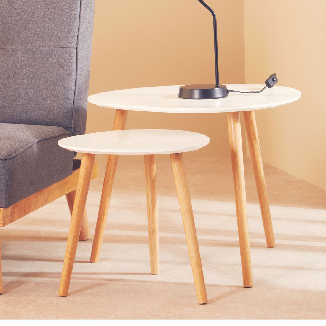 Two round side tables with wooden legs against a beige wall.
