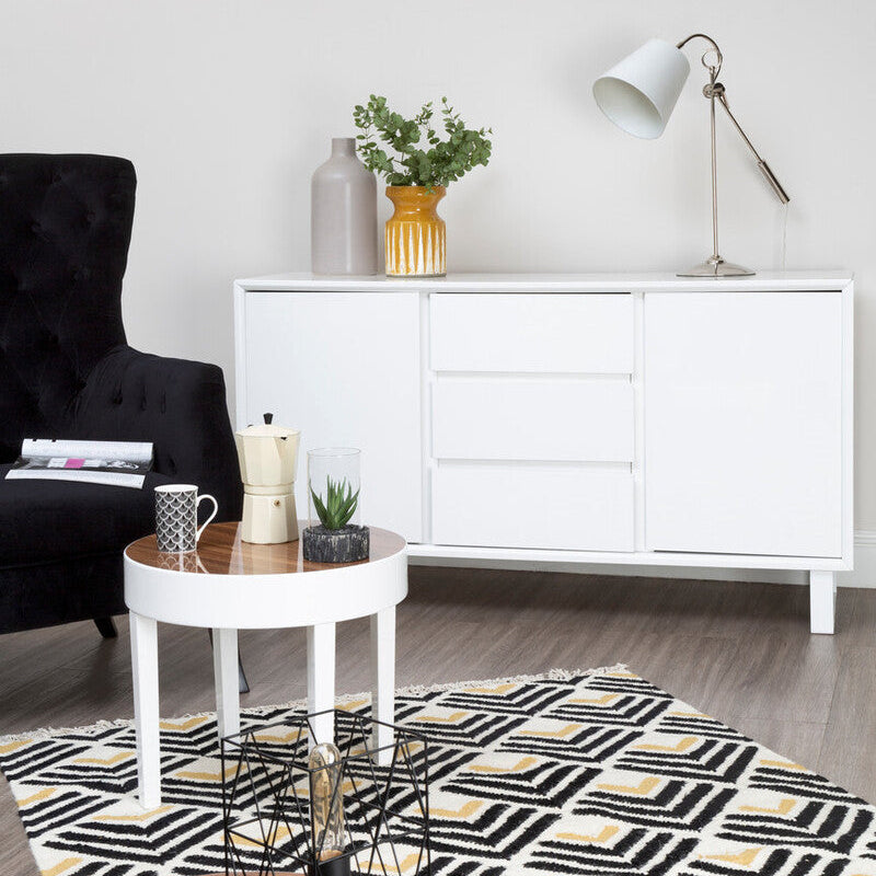 Modern living room with a white sideboard, black armchair, and decorative items.