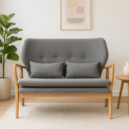 Gray sofa with wooden armrests in a room with a plant and side table.