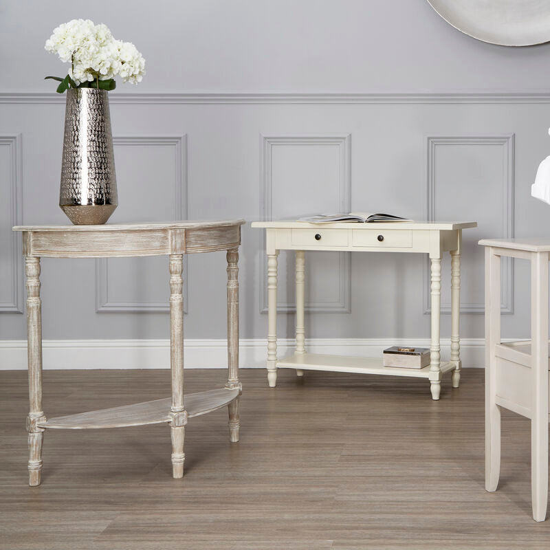 Three white console tables with decorative items against a gray wall.