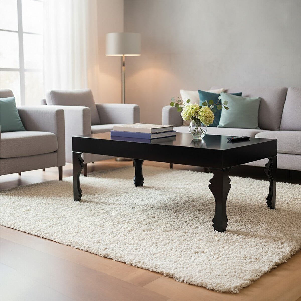 Modern living room with a black coffee table, gray sofa, and white rug.