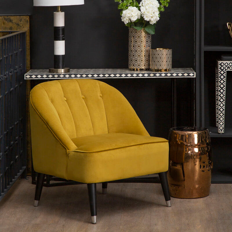 Yellow armchair in a room with a dark wall, lamp, and decorative items.