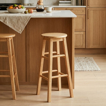 Wooden bar stools in a kitchen setting with a counter and fruit bowl.