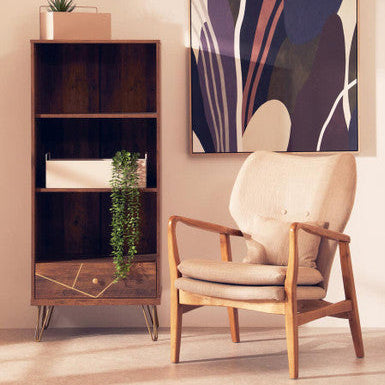 Wooden bookshelf with decorative items and a beige armchair in a room with abstract art on the wall.