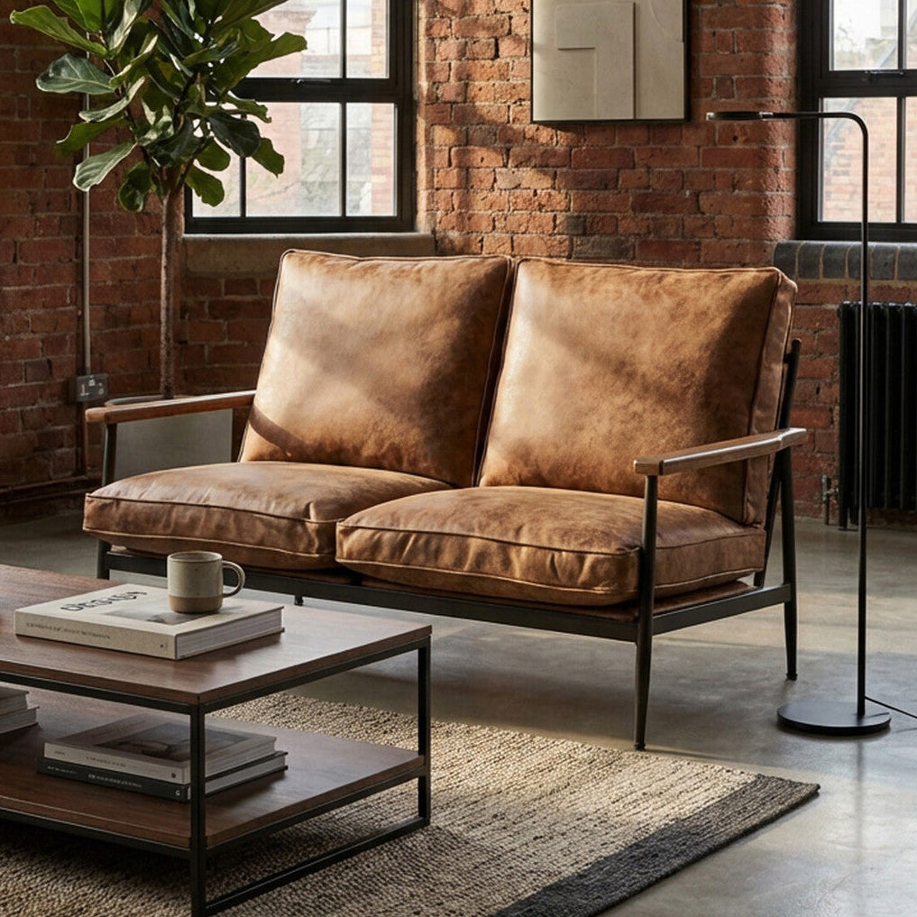 Brown leather sofa in a modern living room with brick walls and a coffee table.