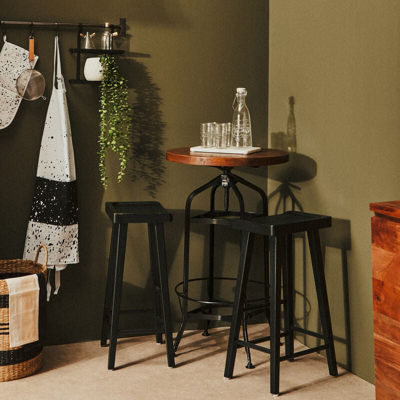 Bar area with black stools, a wooden table, and green wall.